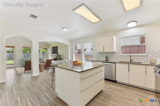 8430 Alvin High Ln, Austin, TX 78729 - kitchen with stainless steel dishwasher, a sink, arched walkways, dark countertops, and plenty of natural light