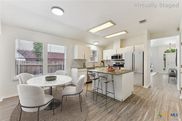 8430 Alvin High Ln, Austin, TX 78729 - kitchen featuring appliances with stainless steel finishes, a center island, light wood-style floors, and vaulted ceiling