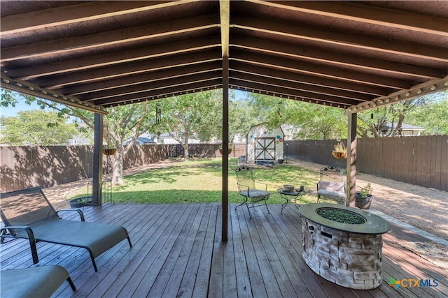 wooden terrace with a yard, a storage shed, and a fire pit