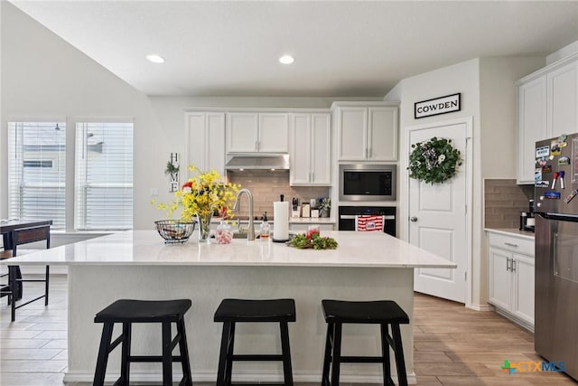 4032 Wild Bloom Rd, Seguin, TX 78155 - kitchen featuring appliances with stainless steel finishes, under cabinet range hood, backsplash, white cabinetry, and recessed lighting