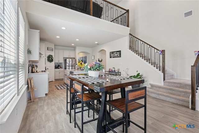 4032 Wild Bloom Rd, Seguin, TX 78155 - dining space with stairway, light wood-style floors, arched walkways, recessed lighting, and a towering ceiling