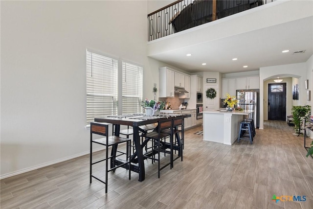 4032 Wild Bloom Rd, Seguin, TX 78155 - dining space with arched walkways, light wood-type flooring, a high ceiling, and recessed lighting
