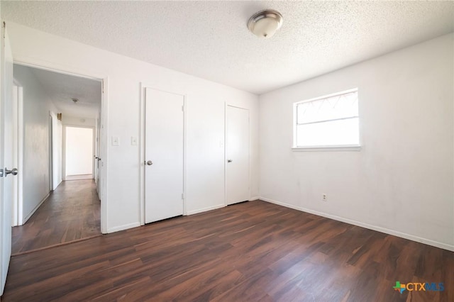 unfurnished bedroom with dark hardwood / wood-style flooring and a textured ceiling