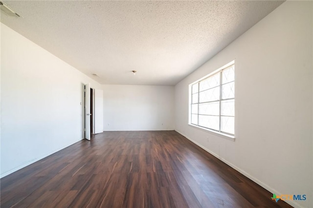 unfurnished room featuring a textured ceiling and dark hardwood / wood-style floors