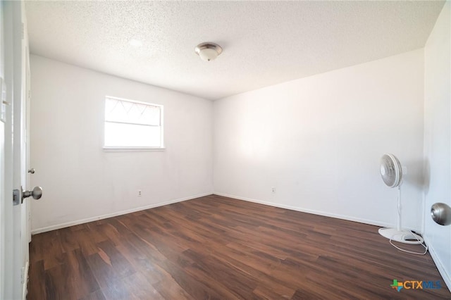 unfurnished room featuring dark wood-type flooring and a textured ceiling