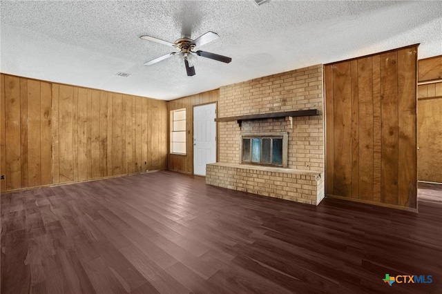 unfurnished living room with a textured ceiling, dark hardwood / wood-style floors, and wood walls