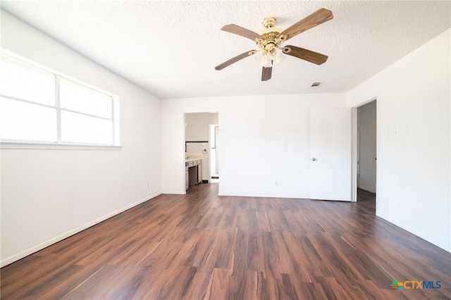 empty room with a textured ceiling, ceiling fan, and dark hardwood / wood-style floors