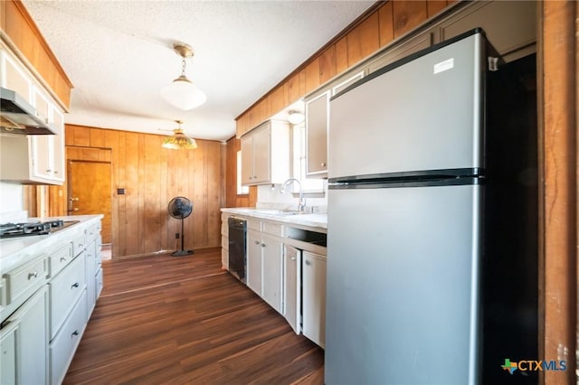 kitchen featuring appliances with stainless steel finishes, dark hardwood / wood-style flooring, sink, decorative light fixtures, and white cabinets