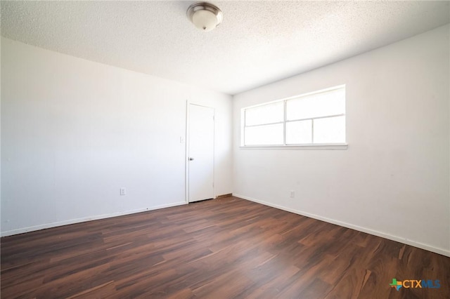 spare room featuring a textured ceiling and dark wood-type flooring