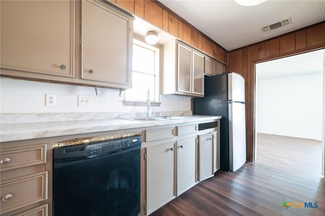 kitchen with a textured ceiling, dark wood-type flooring, sink, black dishwasher, and stainless steel refrigerator