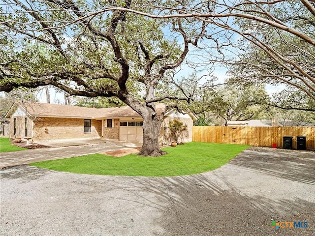 exterior space with brick siding, a front lawn, fence, a garage, and driveway