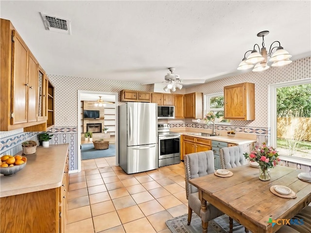 kitchen featuring visible vents, wallpapered walls, light countertops, appliances with stainless steel finishes, and a sink