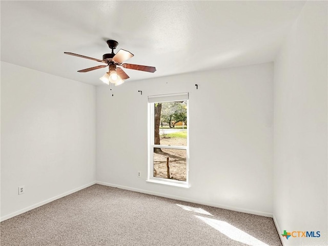 carpeted spare room featuring baseboards and ceiling fan