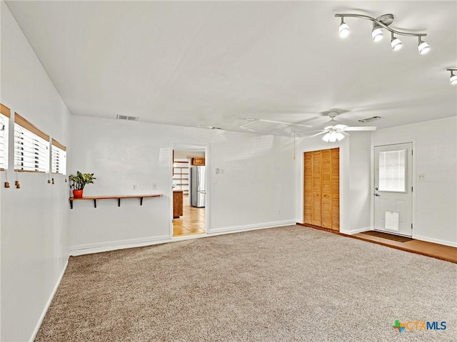 unfurnished room featuring a ceiling fan, baseboards, visible vents, carpet floors, and attic access