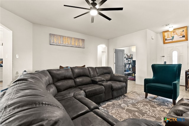 living area with light tile patterned floors, visible vents, arched walkways, and a ceiling fan