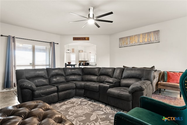 living room with a ceiling fan and arched walkways