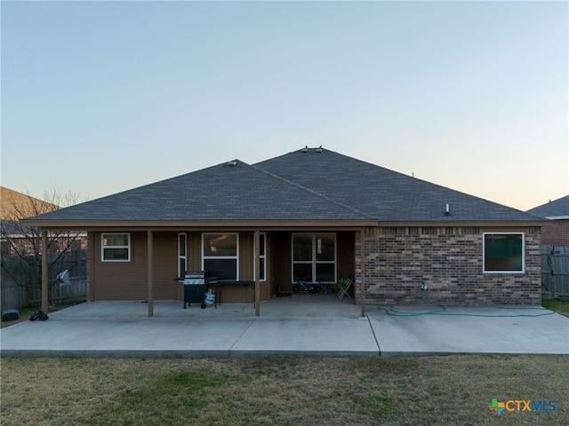 back of property featuring a patio area, brick siding, a lawn, and fence