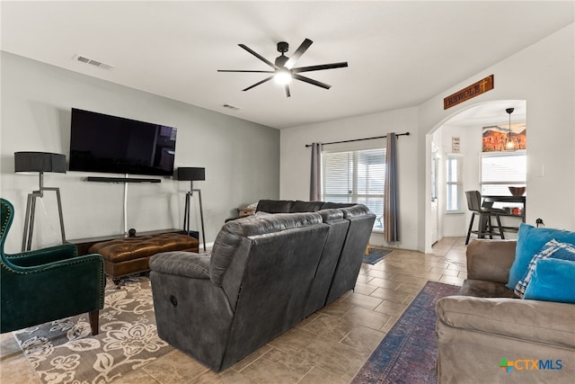 living area featuring a ceiling fan, arched walkways, and visible vents