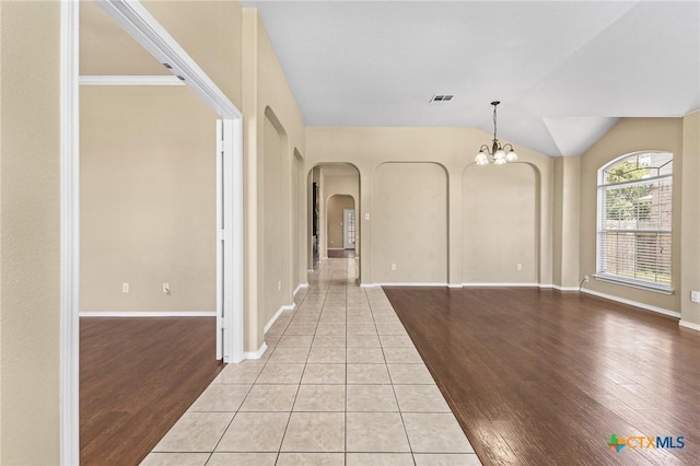 2003 Schottische Ln, Killeen, TX 76542 - empty room featuring arched walkways, a chandelier, light wood-style floors, lofted ceiling, and baseboards