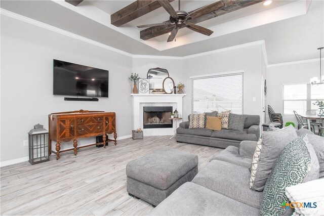 living room with light hardwood / wood-style floors, ceiling fan, crown molding, and a tray ceiling