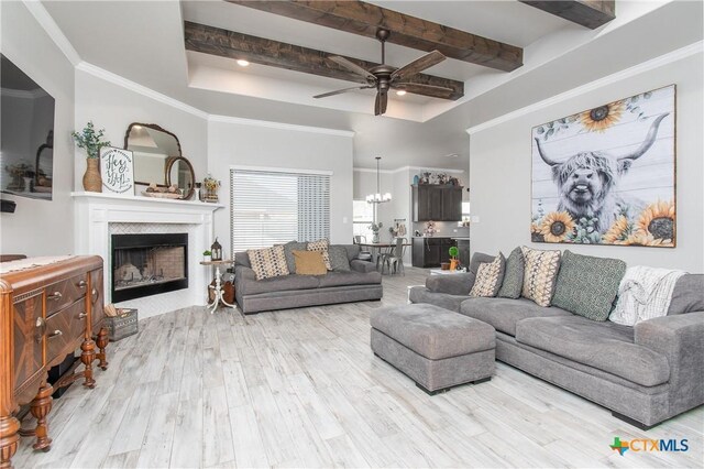 living room featuring light wood-type flooring, washer / dryer, crown molding, and ceiling fan with notable chandelier