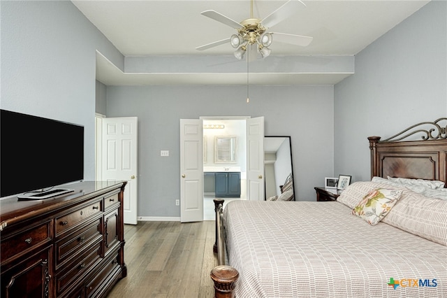 bedroom with dark wood finished floors, connected bathroom, baseboards, and ceiling fan