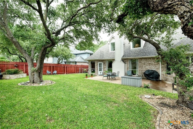 rear view of house featuring a patio, a fenced backyard, a yard, a shingled roof, and brick siding