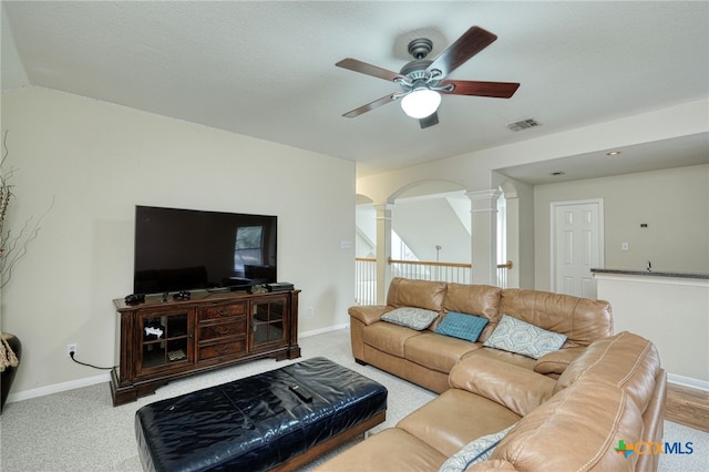 living room with carpet floors, baseboards, ceiling fan, and decorative columns