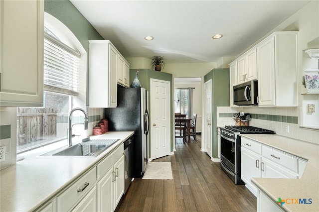 kitchen with a sink, stainless steel appliances, light countertops, and white cabinetry