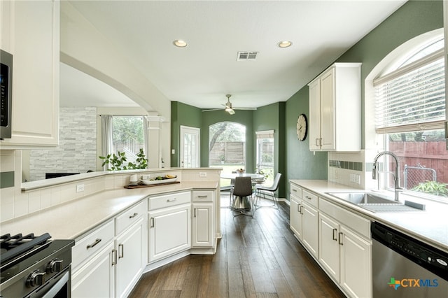 kitchen featuring a sink, white cabinetry, appliances with stainless steel finishes, a peninsula, and decorative backsplash