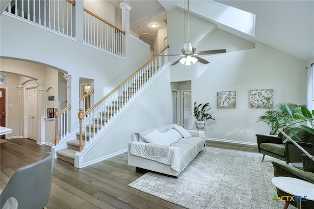 living area with stairway, ceiling fan, ornate columns, and wood finished floors