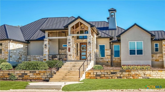 view of front of property featuring a standing seam roof, stone siding, metal roof, and stucco siding