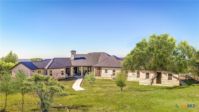 back of property with stone siding, a lawn, and a standing seam roof