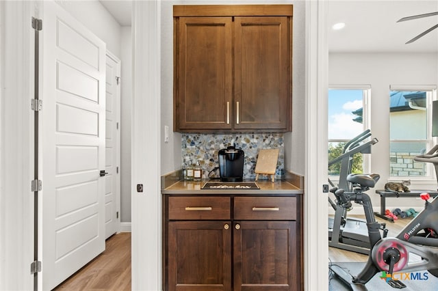 bar featuring backsplash, ceiling fan, and light hardwood / wood-style flooring