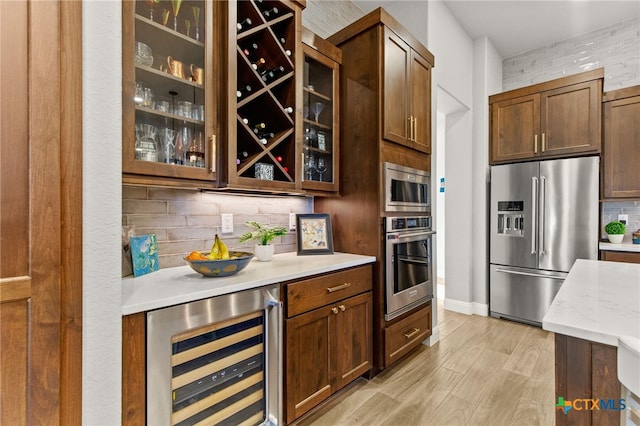 kitchen featuring wine cooler, backsplash, appliances with stainless steel finishes, and light hardwood / wood-style floors