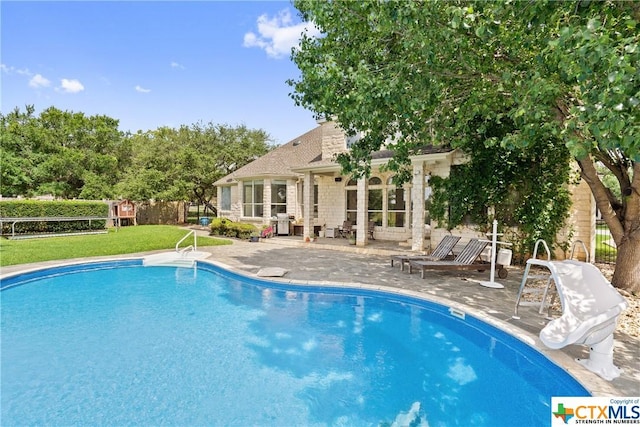 view of pool with a patio, a water slide, fence, a lawn, and a fenced in pool