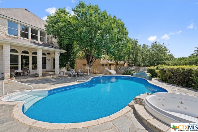 view of pool featuring a fenced in pool, a patio, fence, a water slide, and a jacuzzi