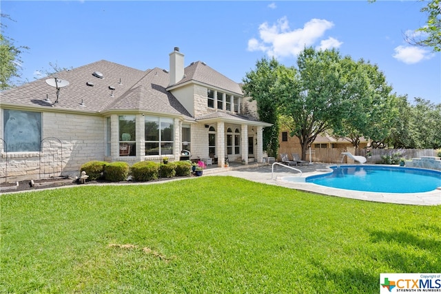 back of house with stone siding, fence, a patio, and a lawn