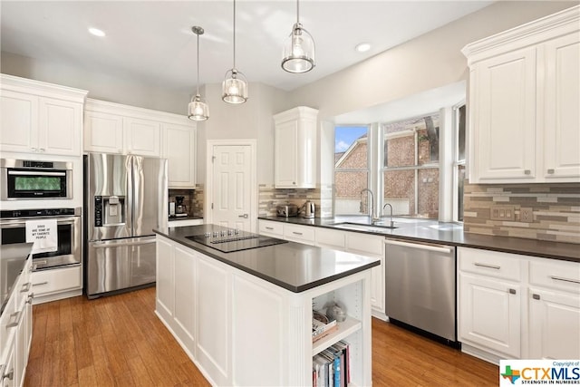 445 Champions Dr, Georgetown, TX 78628 - kitchen with stainless steel appliances, a sink, dark countertops, a kitchen island, and recessed lighting