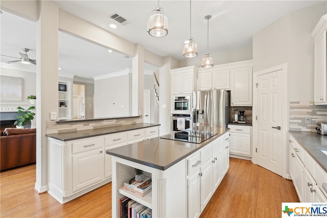 kitchen with light wood-style flooring, stainless steel appliances, visible vents, a center island, and dark countertops