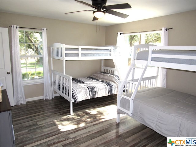 bedroom featuring ceiling fan, dark hardwood / wood-style floors, and multiple windows