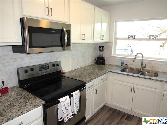 kitchen with black electric range, dark wood-type flooring, light stone counters, sink, and white cabinetry