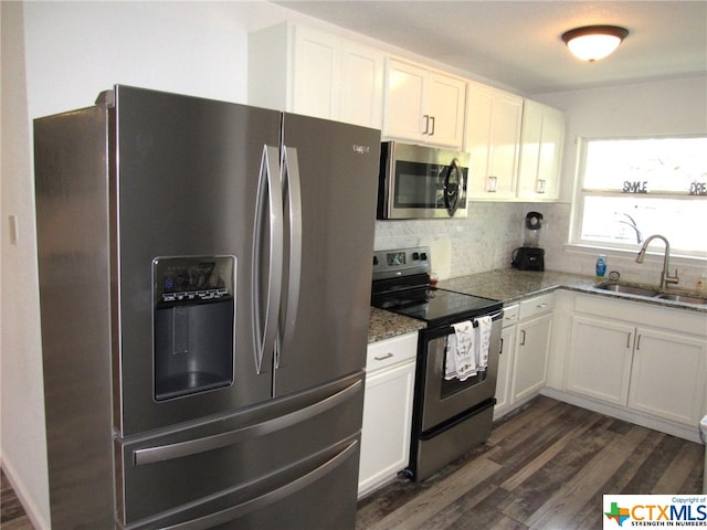 kitchen featuring dark stone counters, white cabinetry, sink, and stainless steel appliances