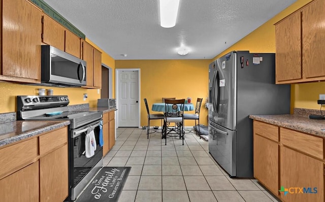 kitchen featuring light tile patterned floors, a textured ceiling, and stainless steel appliances