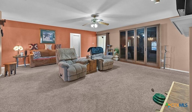 carpeted living area with baseboards and a ceiling fan