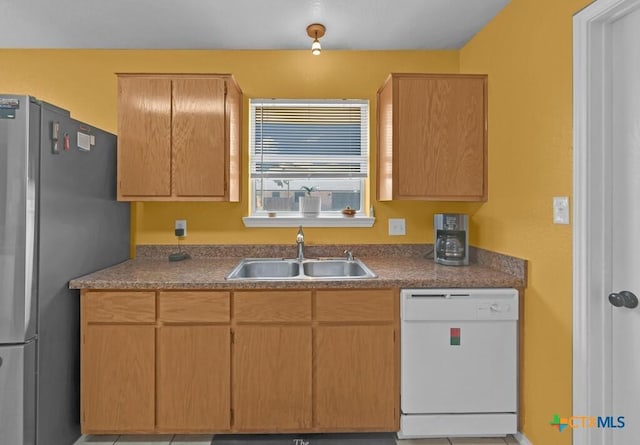 kitchen with white dishwasher, freestanding refrigerator, and a sink