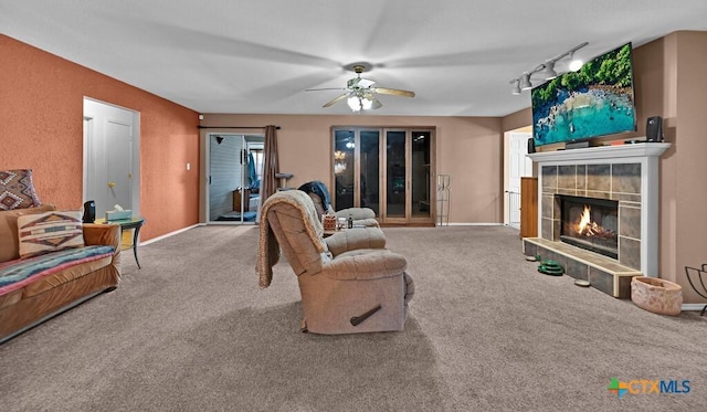 living room with baseboards, a fireplace, ceiling fan, track lighting, and carpet flooring