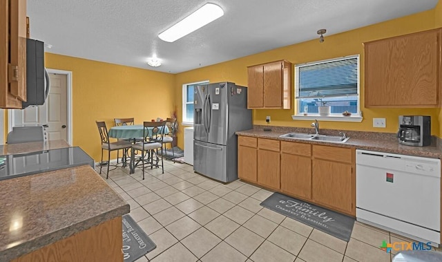 kitchen featuring a sink, dishwasher, stainless steel refrigerator with ice dispenser, and light tile patterned floors