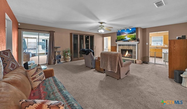 living area featuring visible vents, carpet flooring, ceiling fan, and a fireplace