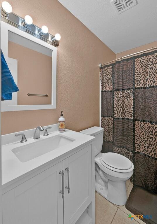 bathroom with vanity, visible vents, tile patterned flooring, toilet, and a textured wall